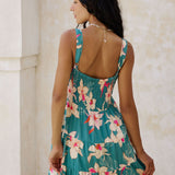woman with brown hair wearing a tiered mini dress in teal with large cream colored orchids.