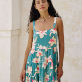 woman with brown hair wearing a tiered mini dress in teal with large cream colored orchids.