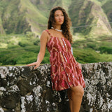 woman with brown hair wearing a red-brown colored mini dress with lei print