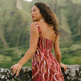 woman with brown hair wearing a red-brown colored mini dress with lei print