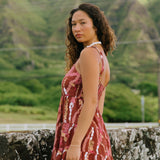 woman with brown hair wearing a red-brown colored mini dress with lei print