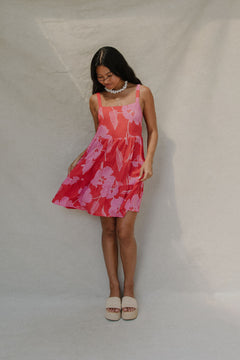 woman with brown hair wearing a red short spaghetti strap dress with pink mao flower pattern
