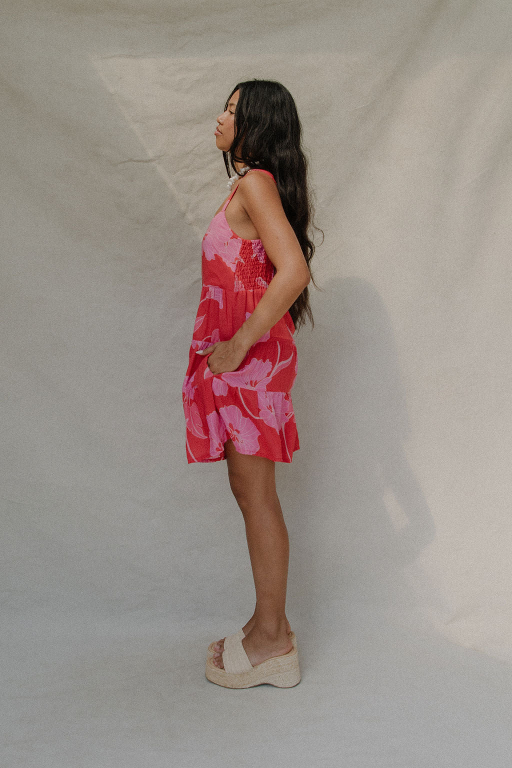 woman with brown hair wearing a red short spaghetti strap dress with pink mao flower pattern