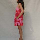 woman with brown hair wearing a red short spaghetti strap dress with pink mao flower pattern