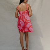 woman with brown hair wearing a red short spaghetti strap dress with pink mao flower pattern