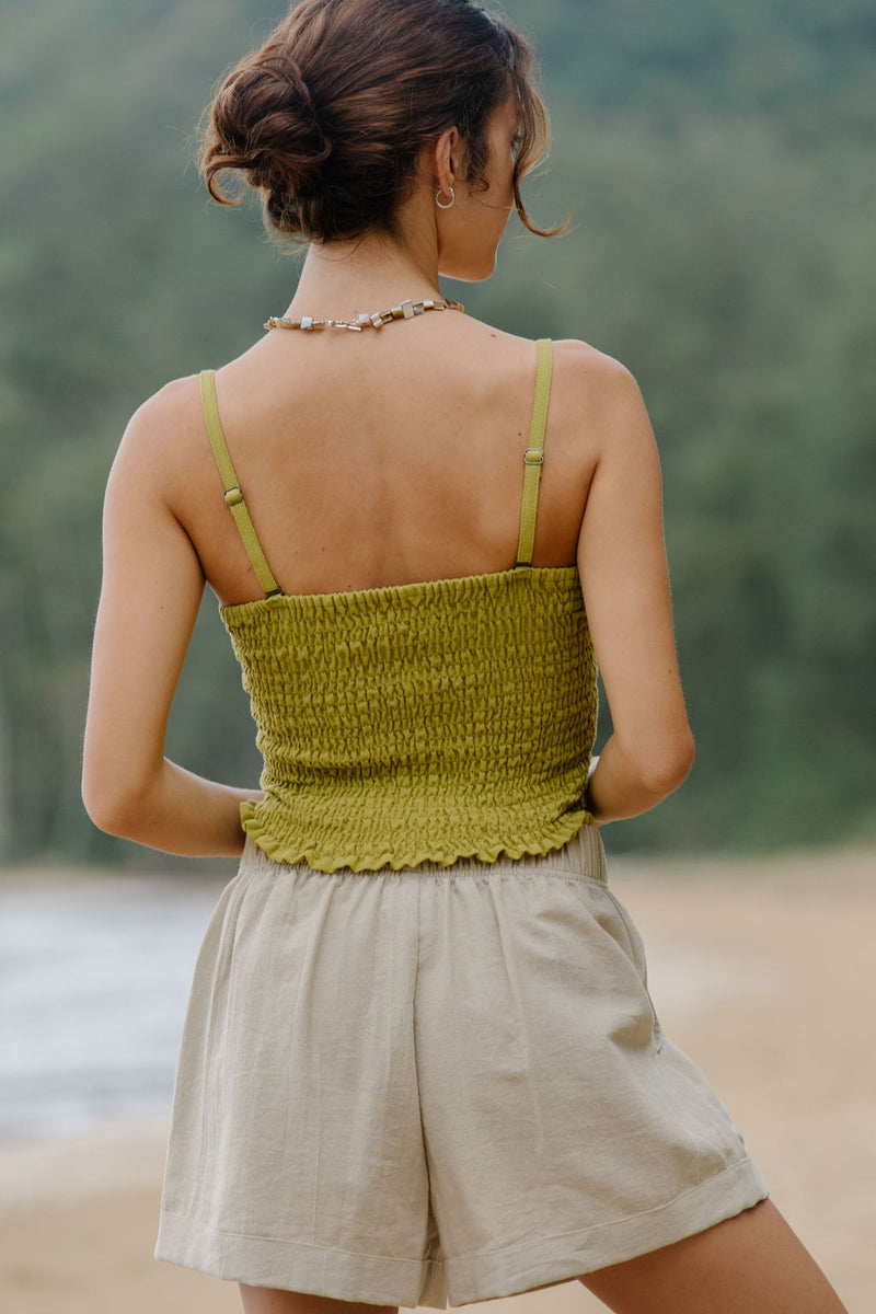 Woman wearing smocked green linen tube top with spaghetti straps and short.