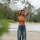 woman with brown hair wearing orange smocked bandeau with removable straps with puakenikeni print