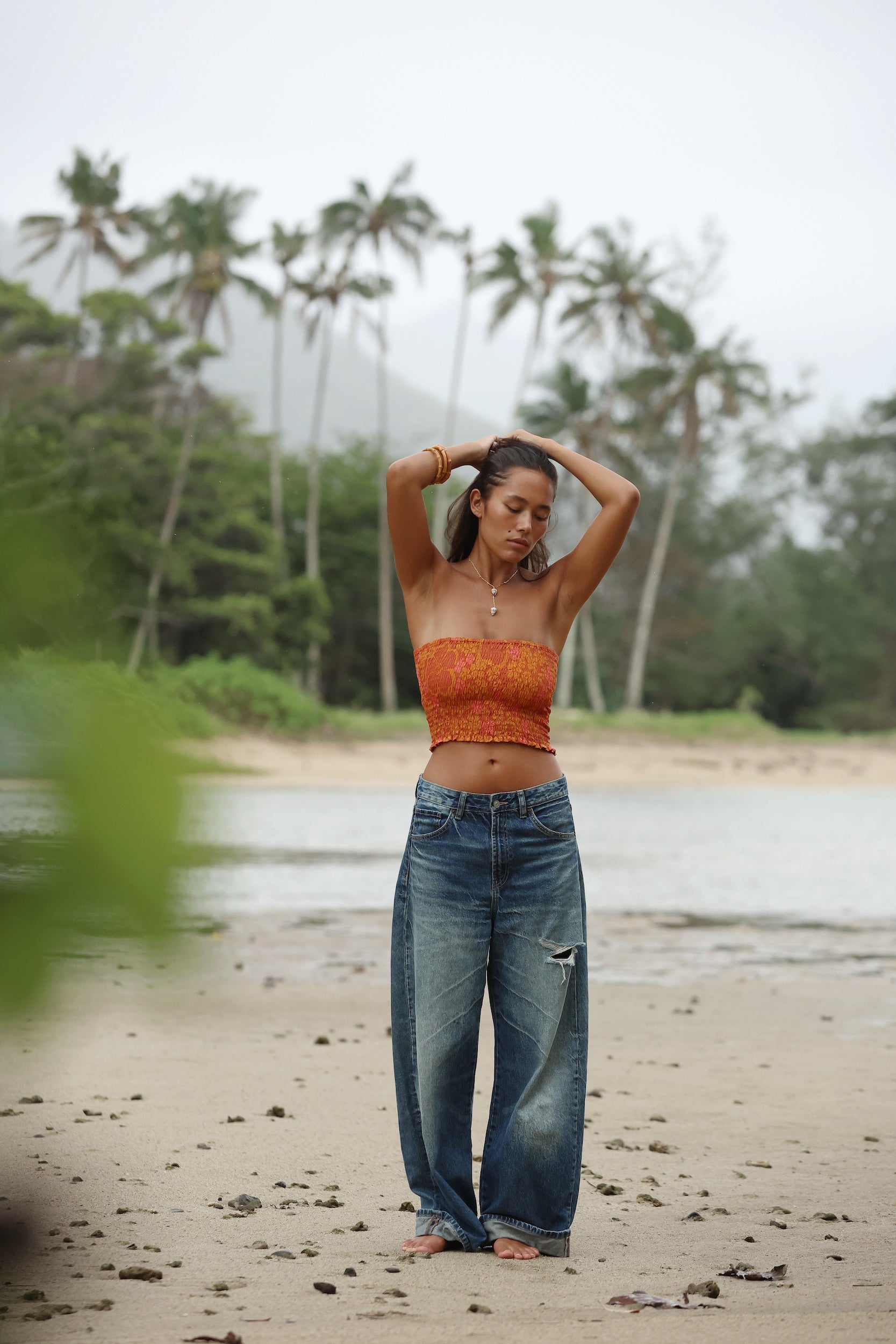 woman with brown hair wearing orange smocked bandeau with removable straps with puakenikeni print