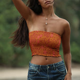 woman with brown hair wearing orange smocked bandeau with removable straps with puakenikeni print