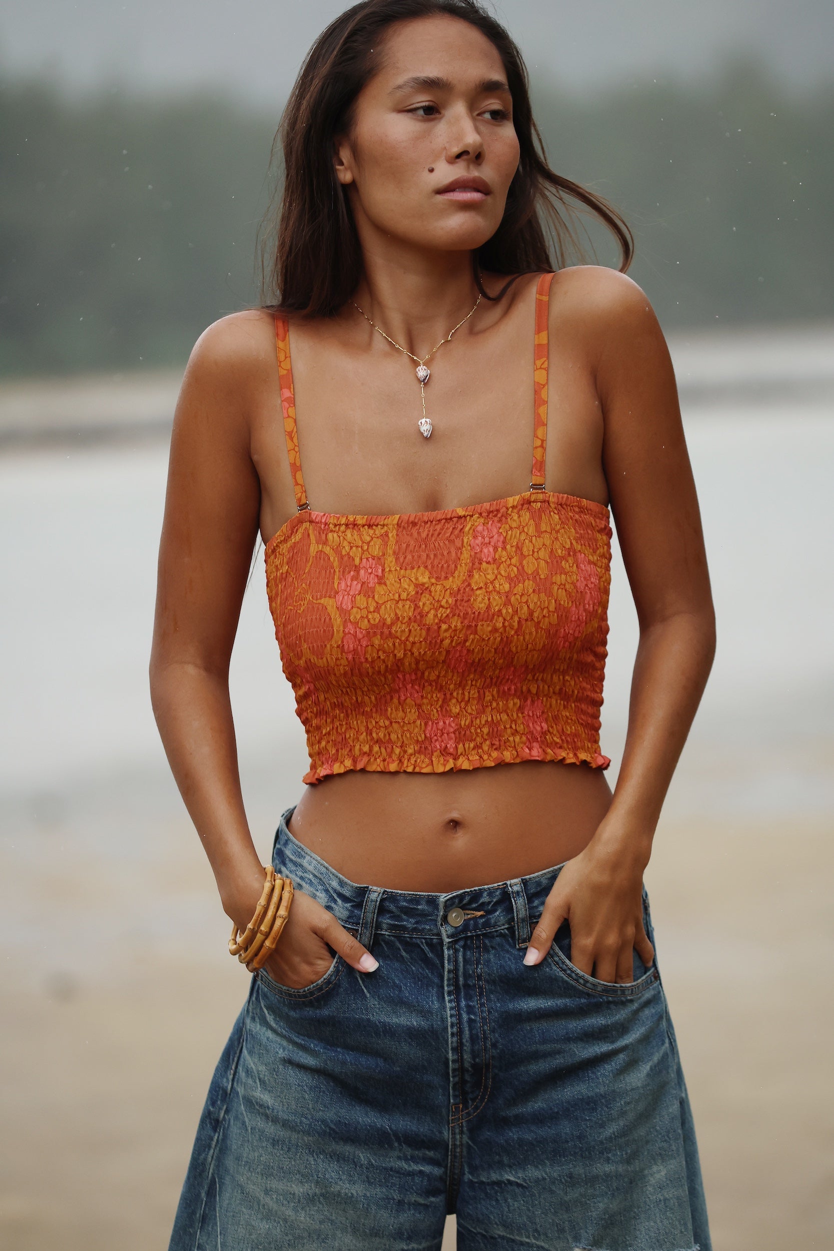 woman with brown hair wearing orange smocked bandeau with removable straps with puakenikeni print