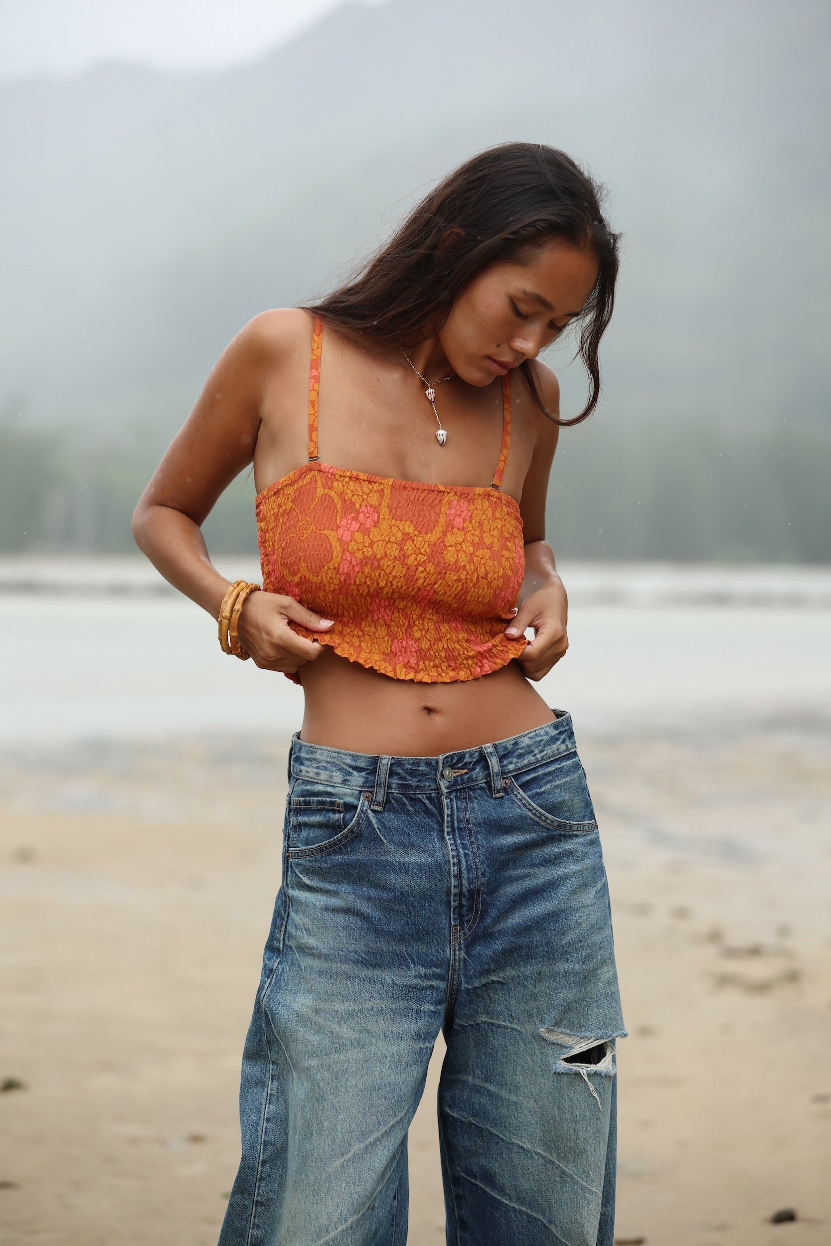 woman with brown hair wearing orange smocked bandeau with removable straps with puakenikeni print
