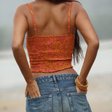 woman with brown hair wearing orange smocked bandeau with removable straps with puakenikeni print