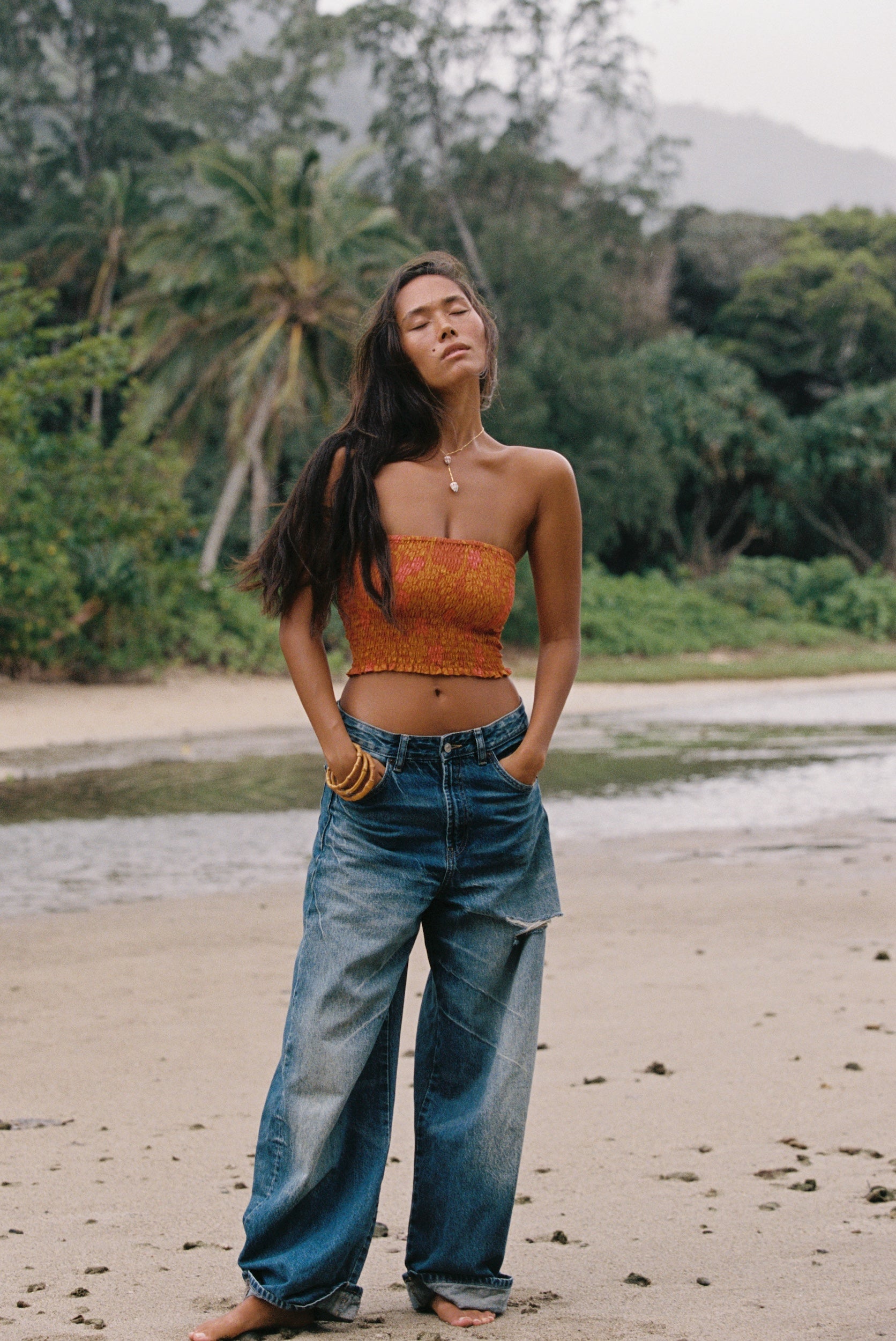woman with brown hair wearing orange smocked bandeau with removable straps with puakenikeni print
