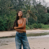 woman with brown hair wearing orange smocked bandeau with removable straps with puakenikeni print