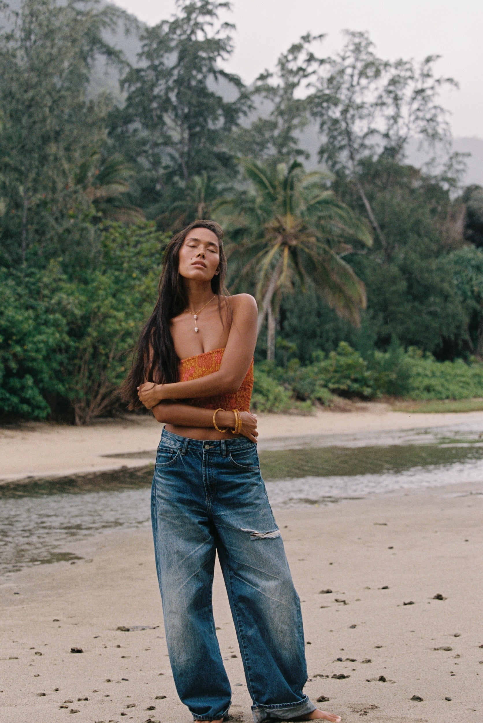 woman with brown hair wearing orange smocked bandeau with removable straps with puakenikeni print