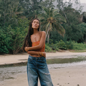 woman with brown hair wearing orange smocked bandeau with removable straps with puakenikeni print