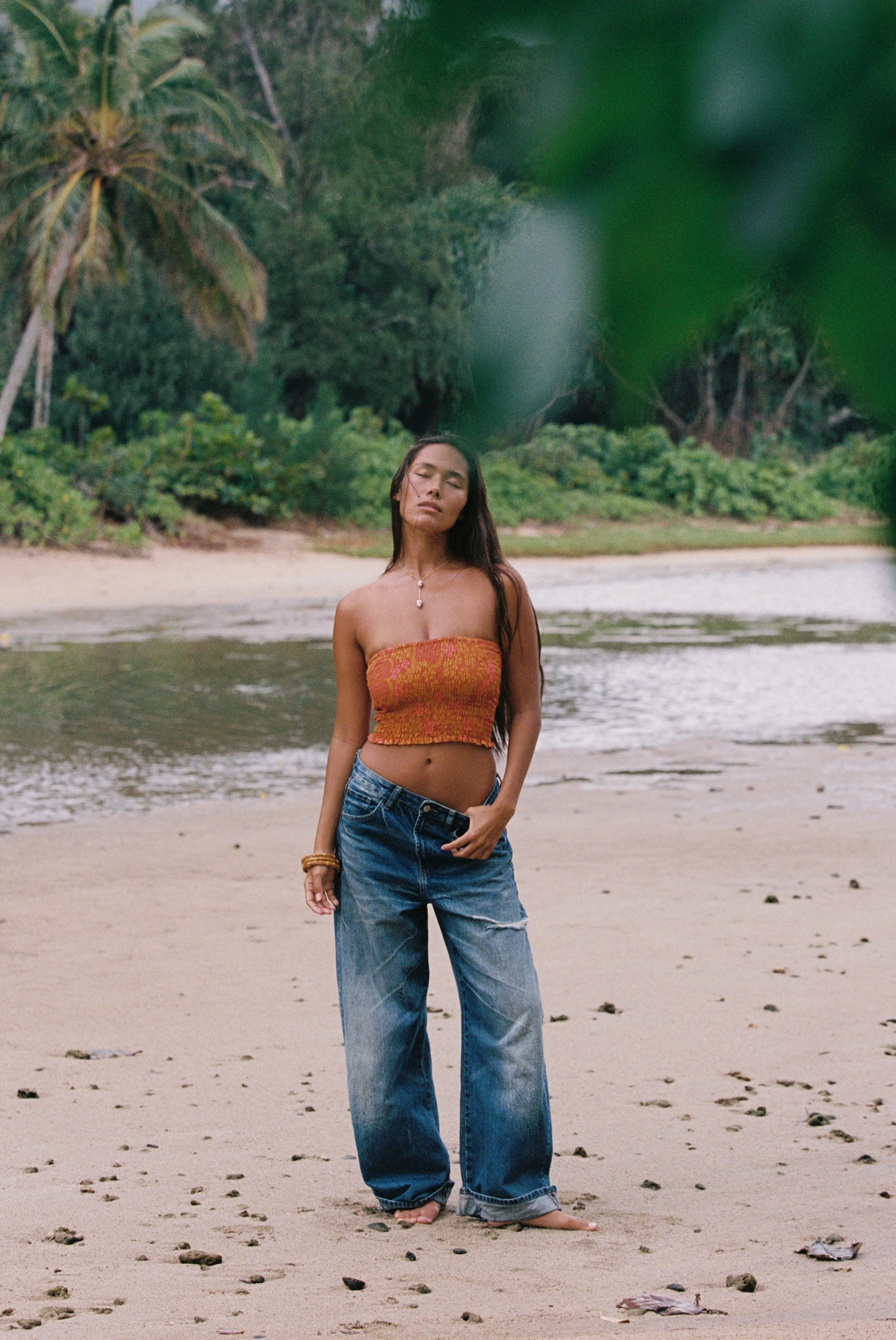 woman with brown hair wearing orange smocked bandeau with removable straps with puakenikeni print