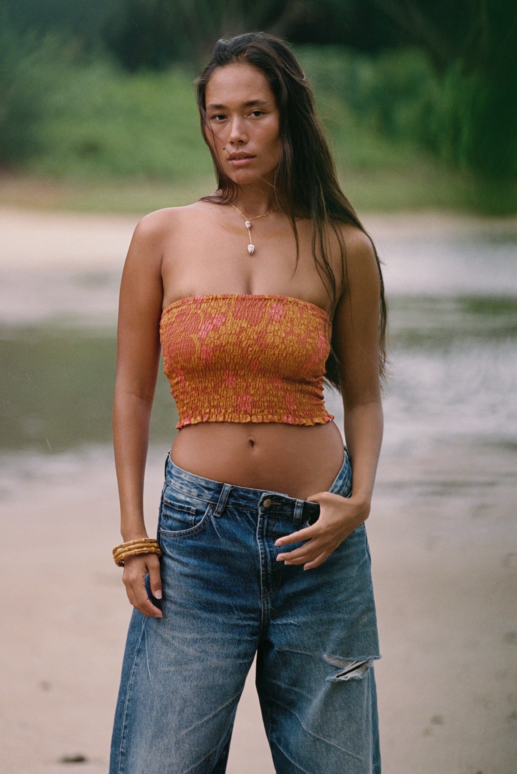 woman with brown hair wearing orange smocked bandeau with removable straps with puakenikeni print