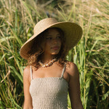 Woman wearing smocked beige linen tube top with spaghetti straps.