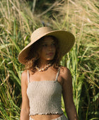 Woman wearing smocked beige linen tube top with spaghetti straps.