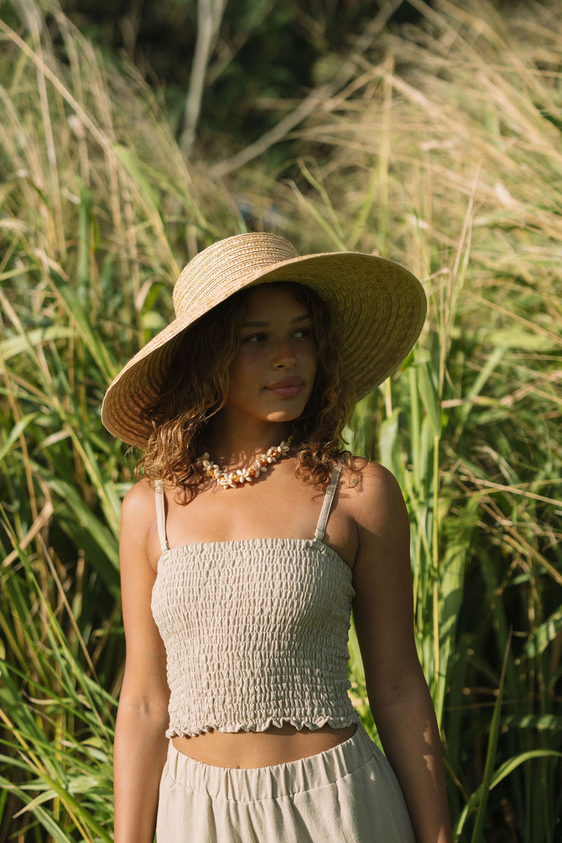 Woman wearing smocked beige linen tube top with spaghetti straps.