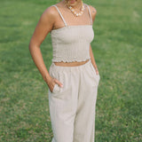 Woman wearing smocked beige linen tube top with spaghetti straps and pant.