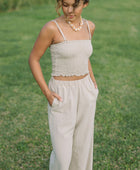 Woman wearing smocked beige linen tube top with spaghetti straps and pant.