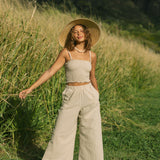 Woman wearing smocked beige linen tube top with spaghetti straps and pant.