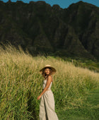 Woman wearing smocked tube top with spaghetti straps and loose pant in beige linen.