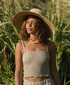 Woman wearing smocked beige linen tube top with spaghetti straps.