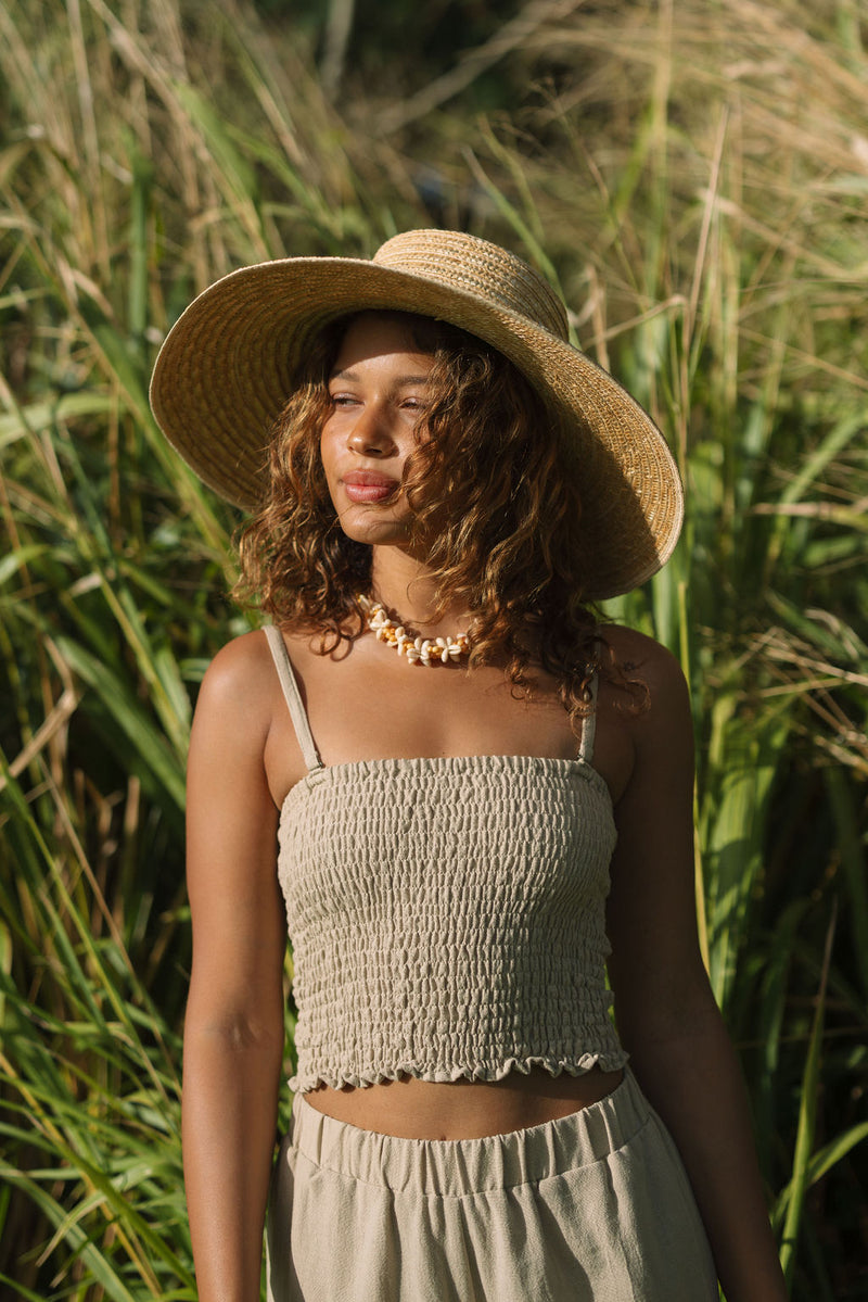 Woman wearing smocked beige linen tube top with spaghetti straps.