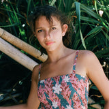 woman with brown hair wearing a bandeau top with removable straps with red ginger and white tiare print
