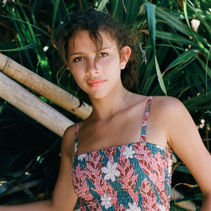 woman with brown hair wearing a bandeau top with removable straps with red ginger and white tiare print