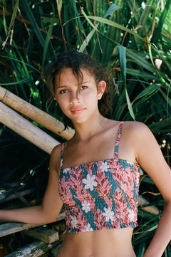 woman with brown hair wearing a bandeau top with removable straps with red ginger and white tiare print