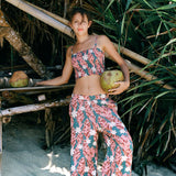 woman with brown hair wearing an elastic waist flowy pant with red ginger and white tiare print