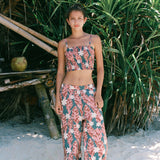 woman with brown hair wearing an elastic waist flowy pant with red ginger and white tiare print