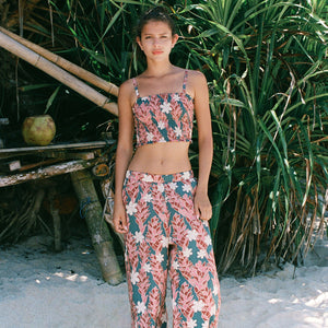 woman with brown hair wearing an elastic waist flowy pant with red ginger and white tiare print
