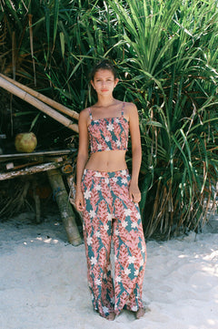 woman with brown hair wearing an elastic waist flowy pant with red ginger and white tiare print