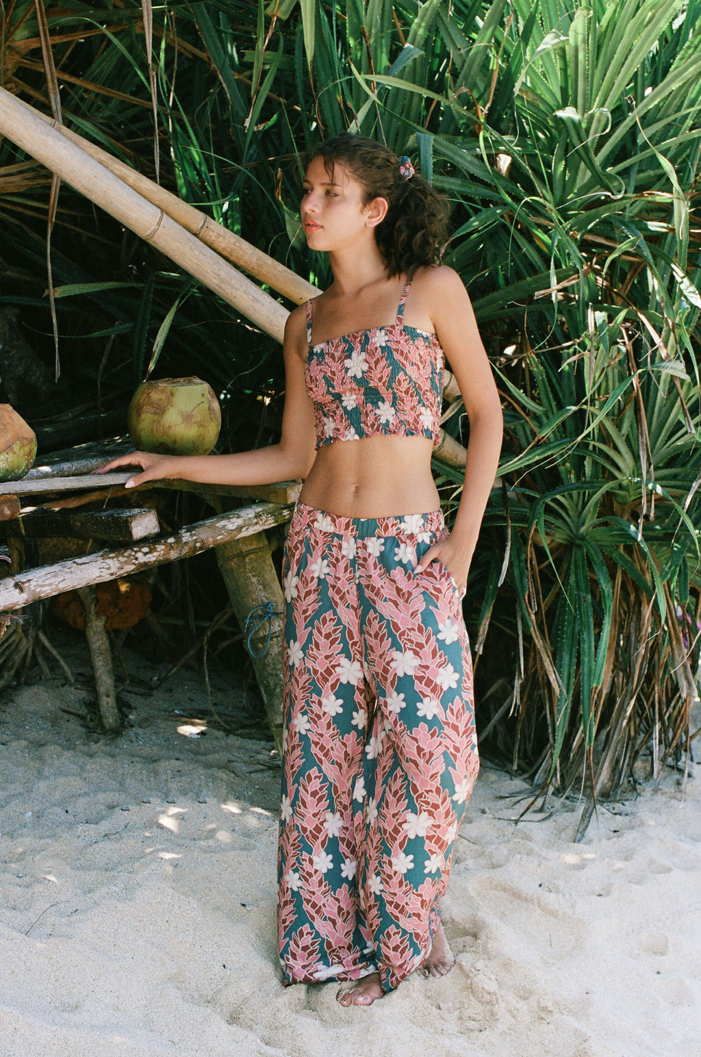 woman with brown hair wearing an elastic waist flowy pant with red ginger and white tiare print
