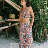 woman with brown hair wearing an elastic waist flowy pant with red ginger and white tiare print