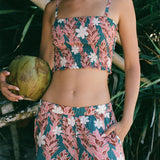 woman with brown hair wearing a bandeau top with removable straps with red ginger and white tiare print