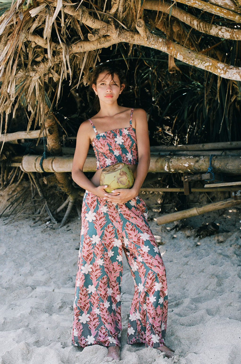 woman with brown hair wearing an elastic waist flowy pant with red ginger and white tiare print