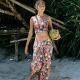 woman with brown hair wearing an elastic waist flowy pant with red ginger and white tiare print