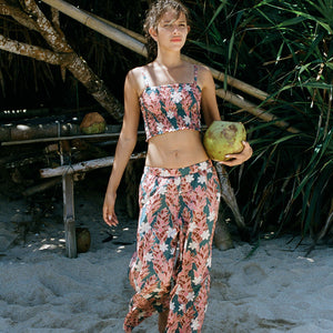 woman with brown hair wearing an elastic waist flowy pant with red ginger and white tiare print