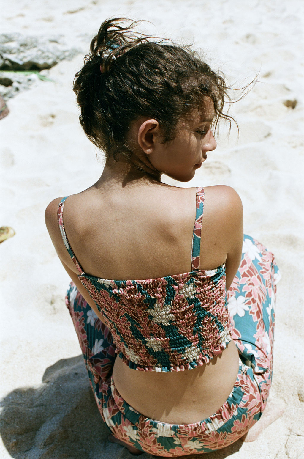 woman with brown hair wearing a bandeau top with removable straps with red ginger and white tiare print