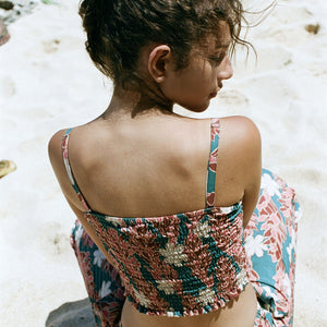 woman with brown hair wearing a bandeau top with removable straps with red ginger and white tiare print