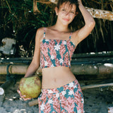 woman with brown hair wearing a bandeau top with removable straps with red ginger and white tiare print