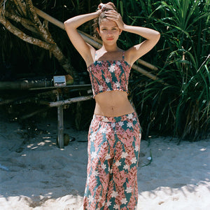 woman with brown hair wearing a bandeau top with removable straps with red ginger and white tiare print