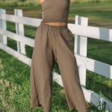 Woman wearing smocked tube top and loose pant in medium brown linen.