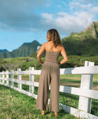 Woman wearing smocked tube top and loose pant in medium brown linen.